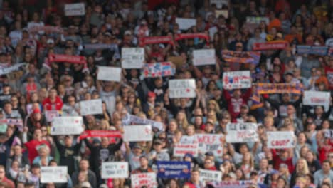 a passionate crowd at a live event: enthusiastic spectators wave signs and show support for their team or cause in a vibrant atmosphere