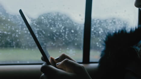 close-up-woman-hands-using-digital-tablet-computer-driving-in-car-browsing-online-messages-reading-social-media-enjoying-mobile-internet-connection-traveling-in-city-on-cold-rainy-day