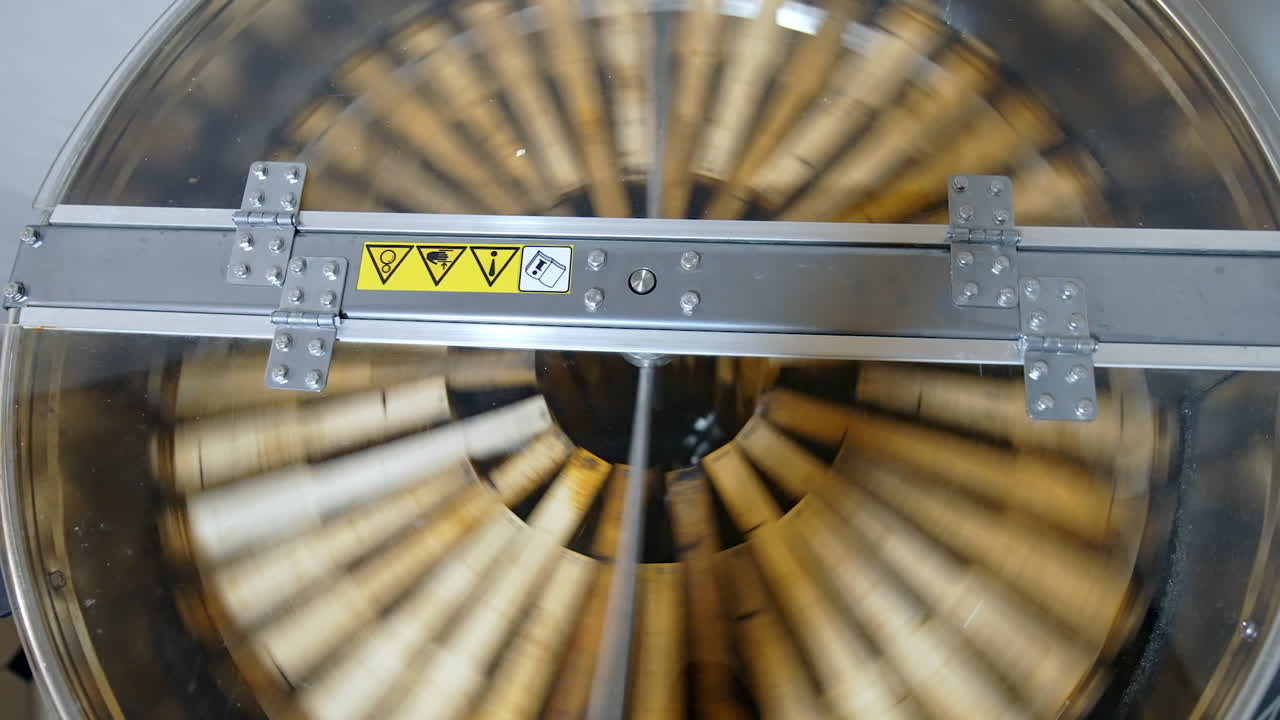 Honey extractor. Centrifuge with frames spinning inside and pumping honey. Industrial equipment to extract fresh honey from honeycombs. Top view.