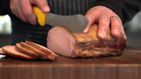 person cutting homemade bacon into slices at the kitchen