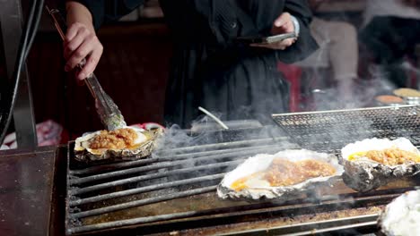 oysters being grilled with flames and smoke