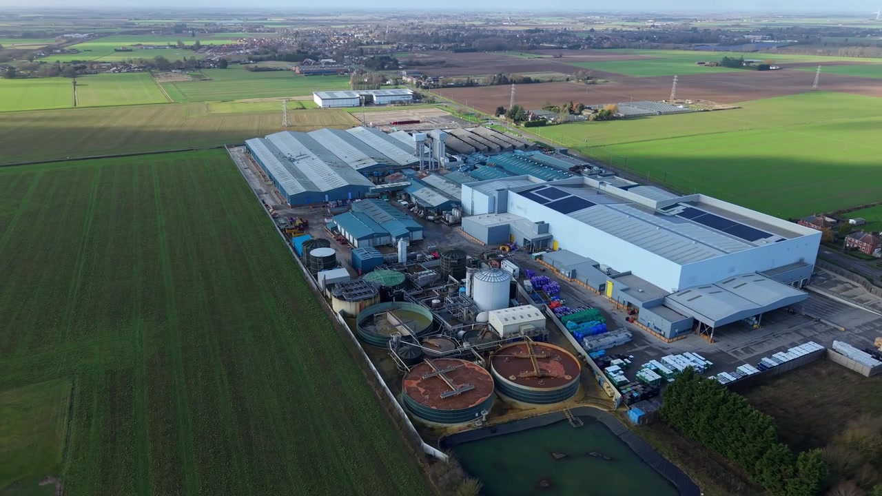 High wide aerial view framing a major manufacturing facility and liquid waste management infrastructure