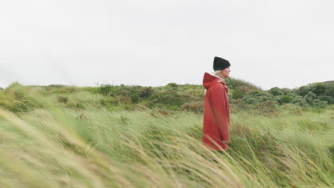 Blondes-Kaukasisches-Mädchen,-Das-Zwischen-Den-Hohen-Strandgräsern-Steht,-Während-Es-In-Die-Ferne-Am-Strand-Von-Ijmuiden,-Niederlande,-Blickt