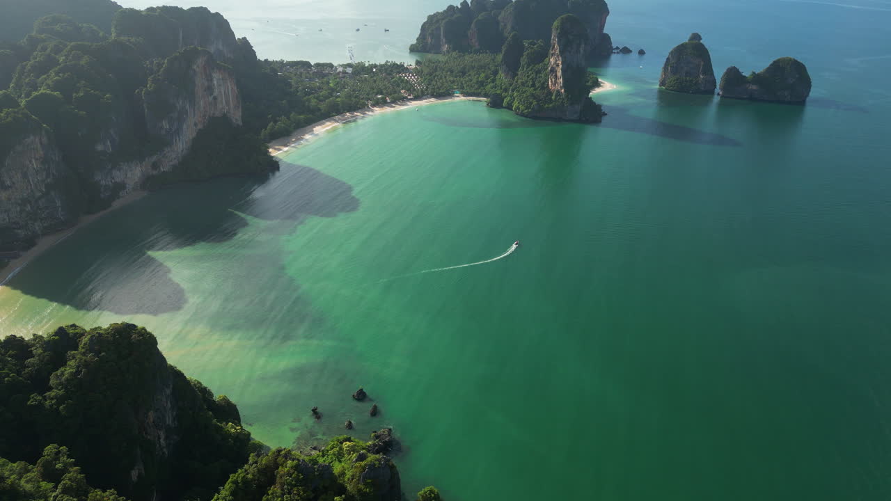 Inquadratura cinematografica con drone dall'alto della famosa spiaggia di Railay in Thailandia con barca da crociera sotto il sole - Ripresa aerea introduttiva di un'isola tropicale asiatica