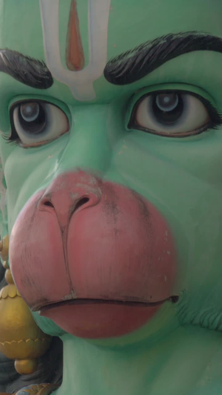 Primo piano del volto della statua verde della divinità Hanuman