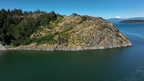 Drone-shot-of-a-boat-passing-by-the-Cap-Sante-Park-viewpoint-in-Anacortes,-Washington