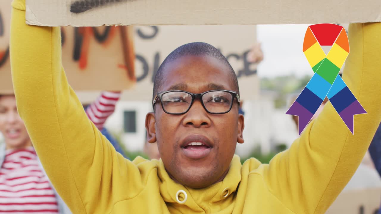 Animation of rainbow ribbon over african american male protester with banner