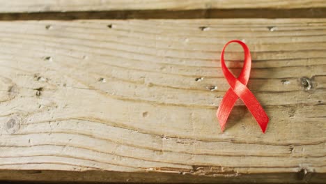 video of close up of red cancer ribbon on wooden background