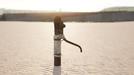 Rusty-old-metal-water-pump-on-sand-beach