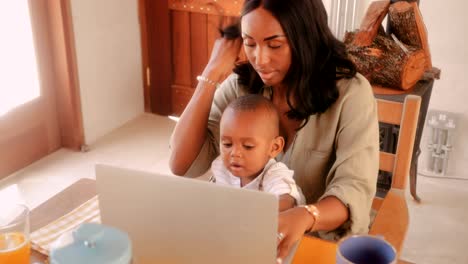 madre empresaria con un hijo pequeño blogueando en la computadora portátil en casa