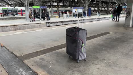 Gray-suitcase-with-a-green-ribbon-stands-alone-on-a-train-platform-without-an-owner