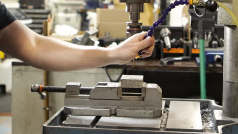 worker operating a pillar drill in an industrial setting, creating precision components