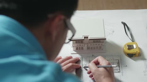 close up of a man engineer drawing blueprint at the office, over shoulder