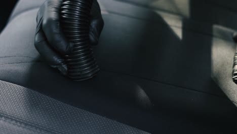 close up of a male wearing black gloves vacuum an black interior car