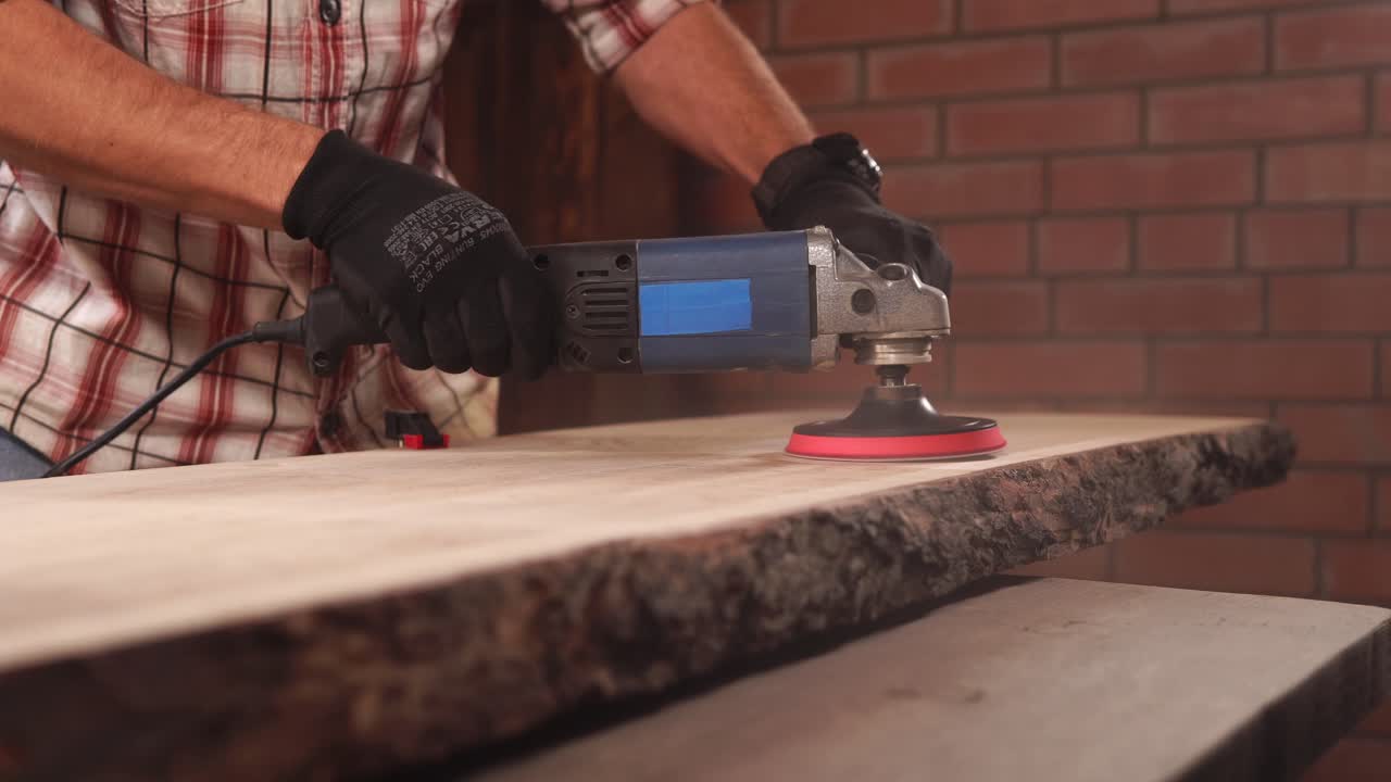un hombre pulindo una losa de madera con una lijadora eléctrica