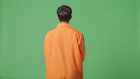 hombre con chaqueta naranja contra pantalla verde