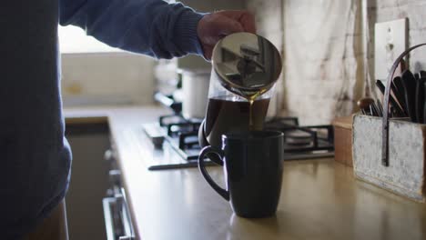 Close-up-of-hands-of-caucasian-man-preparing-coffee-in-kitchen-at-home