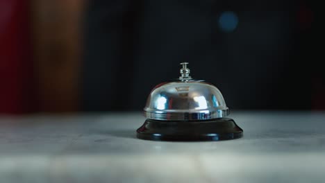 Hand-strikes-the-bell-at-the-reception-desk