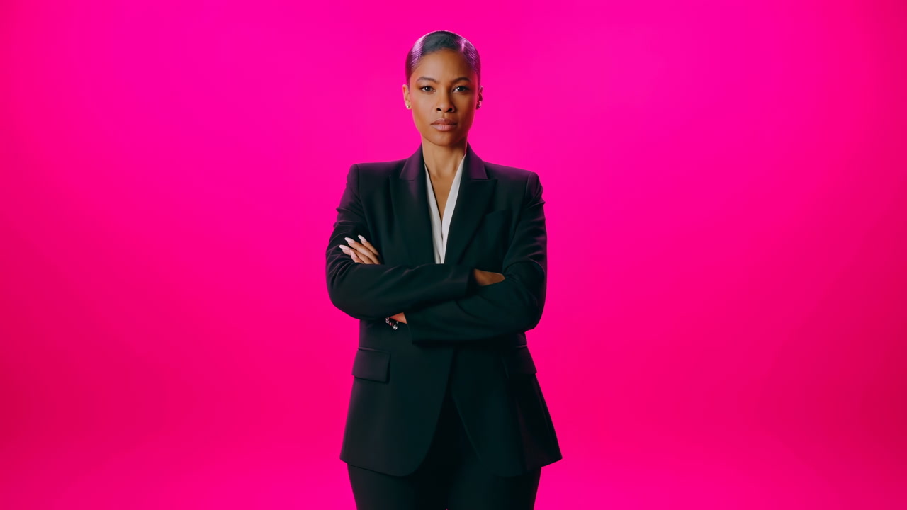 Woman Executive Standing Arms Crossed Against Vibrant Magenta Background Wearing Tailored Black Suit,