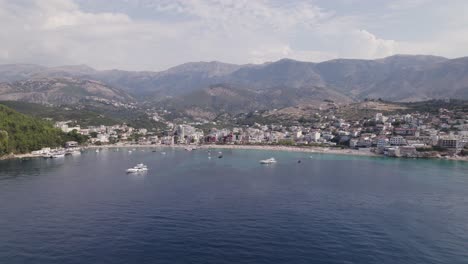 Antena-Acercándose-A-La-Playa-De-Arena-Contra-Las-Montañas,-Himare,-Albania