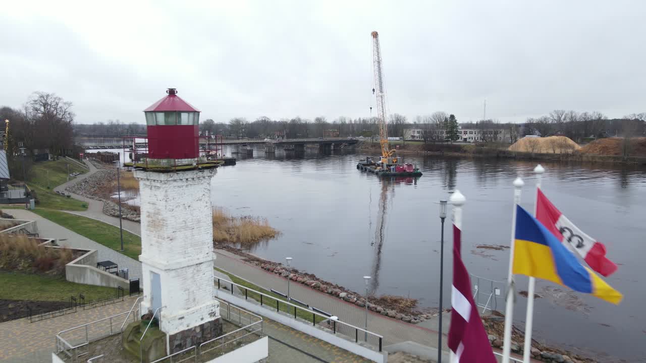 Aerial photograph of Salacgrīva, a coastal city in Latvia, featuring residential buildings, industrial areas, and a riverbank. Ideal for urban or geographical studies.