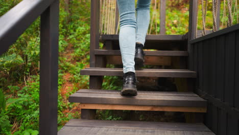 dama sube las escaleras a la casa de gampling. cada paso acercando el abrazo de bienvenida de la cabaña. piernas de mujer en vaqueros y en zapatos deportivos regresa de la caminata