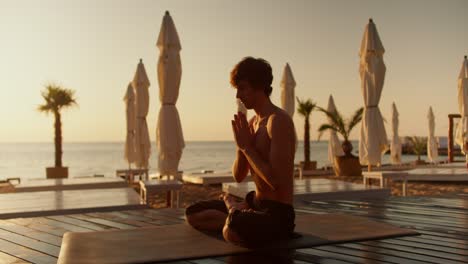 el tipo medita en una alfombra especial en una playa soleada por la mañana. armonía de cuerpo y mente. estilo zen