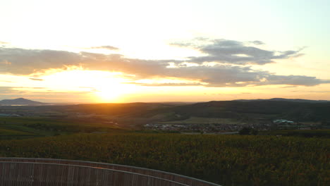 Gipfel-Und-Aussicht-Vom-Aussichtspunkt-Kobylí-Gipfel-Während-Des-Sonnenuntergangs-Mit-Blick-Auf-Die-Holzkonstruktion-Im-Hintergrund-Der-Sonne-Und-Eines-Bauernhofs-Mit-Weinreben,-Die-Sich-Bewegende-Wolken-Gebiet-Von-Südmähren