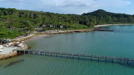 Antenne,-Pfanne,-Drohnenaufnahme-Eines-Hölzernen-Piers-Und-Gebäudes,-An-Einem-Paradiesischen-Strand,-An-Einem-Sonnigen-Tag,-In-Koh-Kood,-Thailand,-Asien