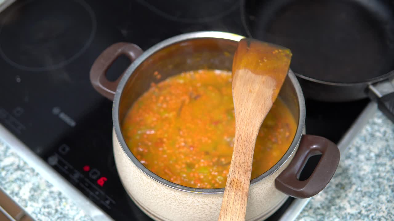 cocinar sopa de lentejas de calabaza en una olla con cucharón de madera en la parte superior