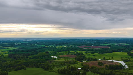 a dramatic aerial timelapse captures moody clouds moving at sunset over the vast countryside near jelgava, latvia, showing a patchwork of forests, fields, and rivers