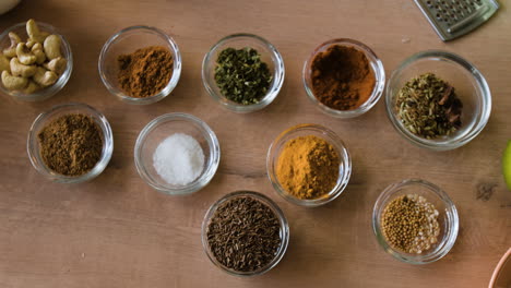 an assortment of spices and ingredients in glass bowls on a wooden table