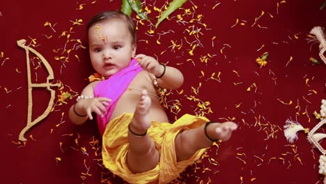 cute indian boy dresses as lord rama with bow and flowers from top angle