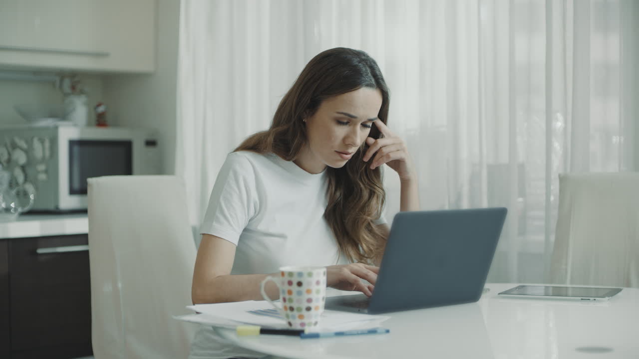 Worried woman working on laptop computer at home