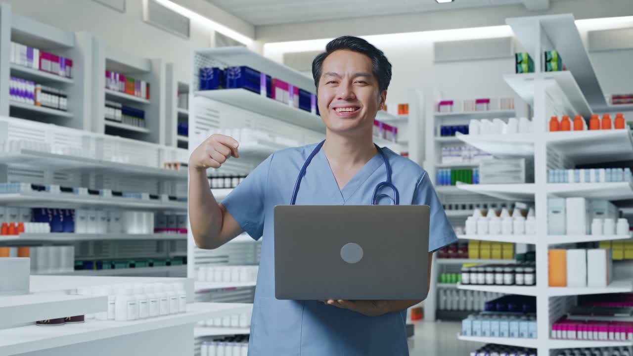 스테토스코프를 들고 있는 아시아 남성 의사 가 약국 에 서 있는 동안 손 에 노트북 을 가리키며 미소 짓고 있다