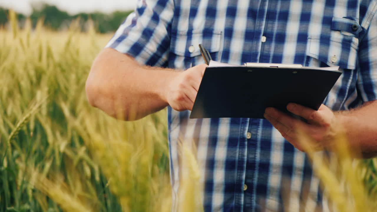 el agricultor firma el documento y le da la mano a un compañero en el fondo de un campo de trigo