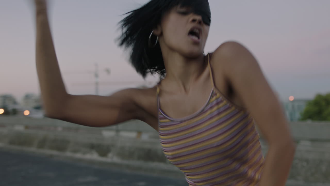 mujer bailarina atractiva bailarina callejera hispana en la ciudad realizando movimientos contemporáneos de hip hop disfrutando de la expresión de danza moderna al atardecer de cerca