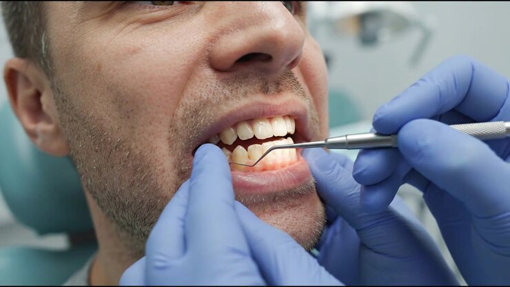 Dentista che esamina i denti del paziente con uno strumento dentale