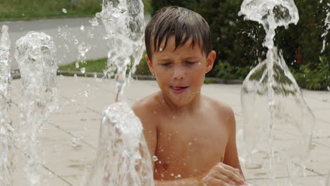 a little boy fascinated by the flow of water from the city fountain