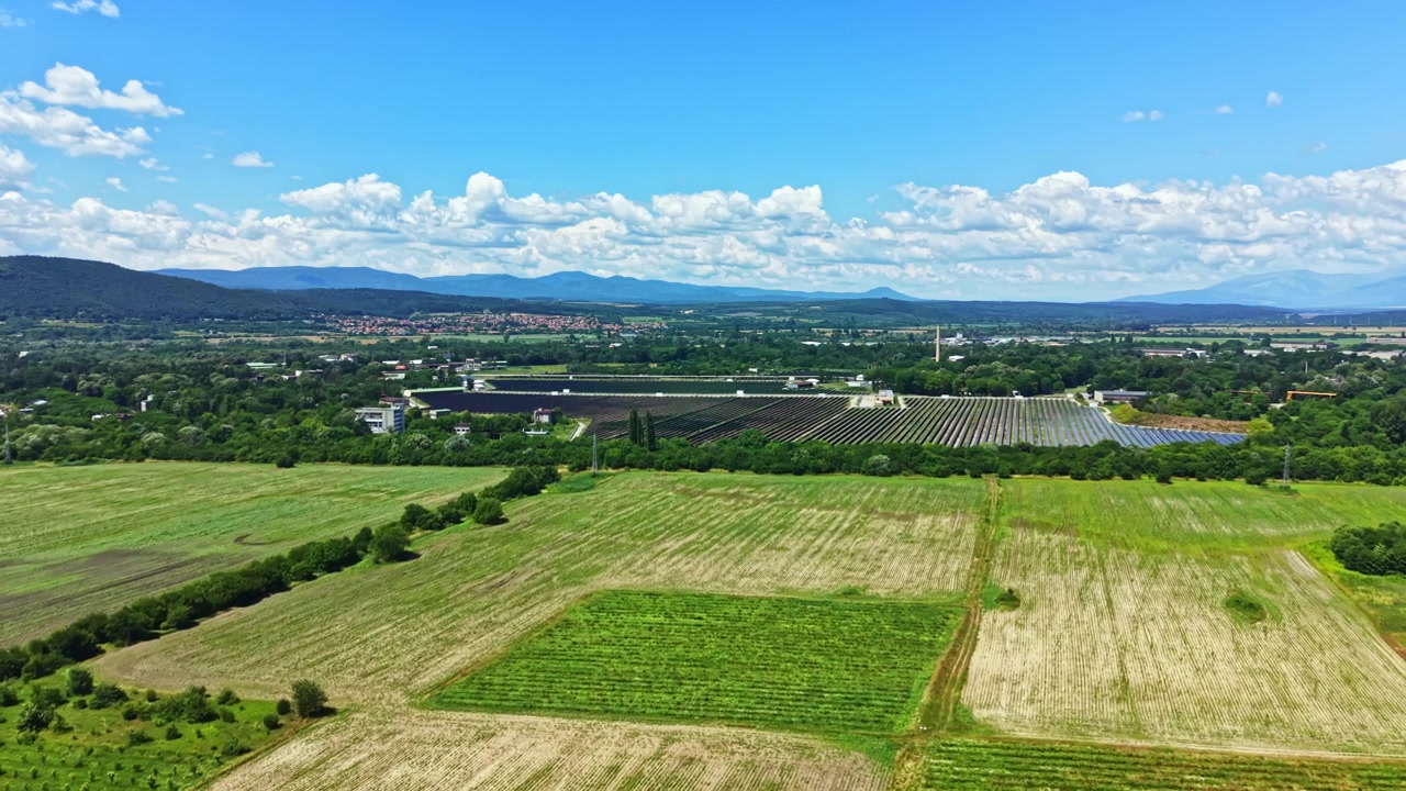 田園地帯では、緑の畑と農場が谷間に広がり、雲が浮かぶ澄み切った空の下、農業の美しさが際立っている。