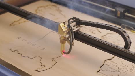 cnc laser cutting machine cuts world map on wooden plank and plywood