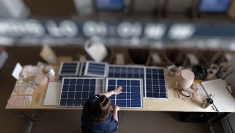 overhead view of a person working with multiple solar panels in a workshop