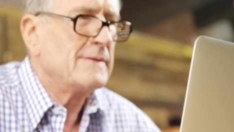 hombre mayor escribiendo mientras usa una computadora portátil en un restaurante 4k