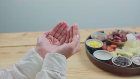 muslim woman. dua before opening fast. iftar food table. evening meal.