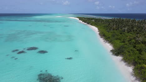 Drone-shot-of-tropical-maldivian-island-beach-with-beautiful-turquoise-waters-of-indian-ocean-on-clear-sunny-day