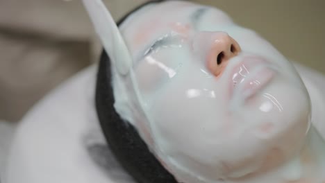 mujer hermosa con máscara facial en un salón de belleza