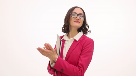 a businesswoman in a magenta jacket presents and gestures while holding a clipboard