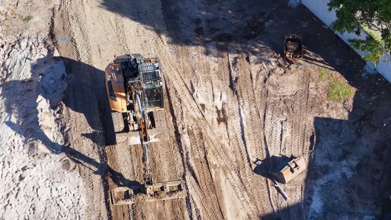 Aerial view of excavator loading dirt into dump truck on sunny Gold Coast construction site