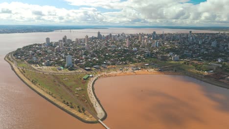 Blick-Aus-Der-Vogelperspektive-Auf-Die-Stadt-Posadas,-Die-Sich-Anmutig-An-Die-Kurven-Des-Mächtigen-Rio-Paraná-Schmiegt-Und-Eine-Malerische-Und-Harmonische-Stadtlandschaft-Schafft