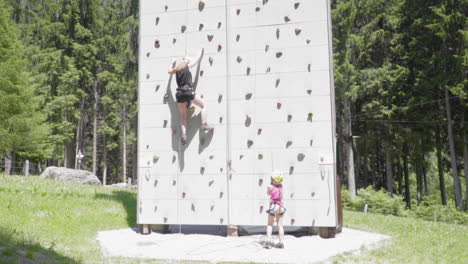 mamá e hija escalan una pared de entrenamiento, cámara lenta